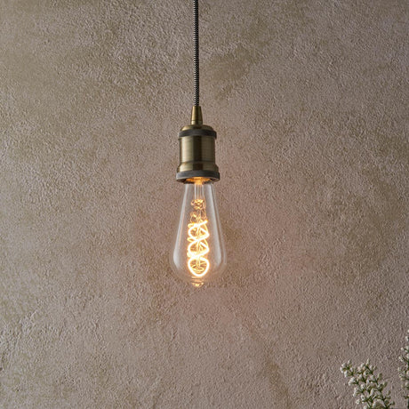 Vintage-style light bulb hanging against a textured beige wall