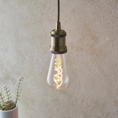 Vintage-style light bulb with brass fixture against a textured wall.