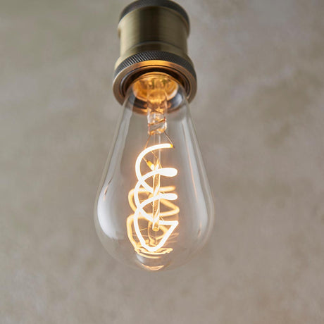 Vintage-style light bulb with coiled filament against a neutral background