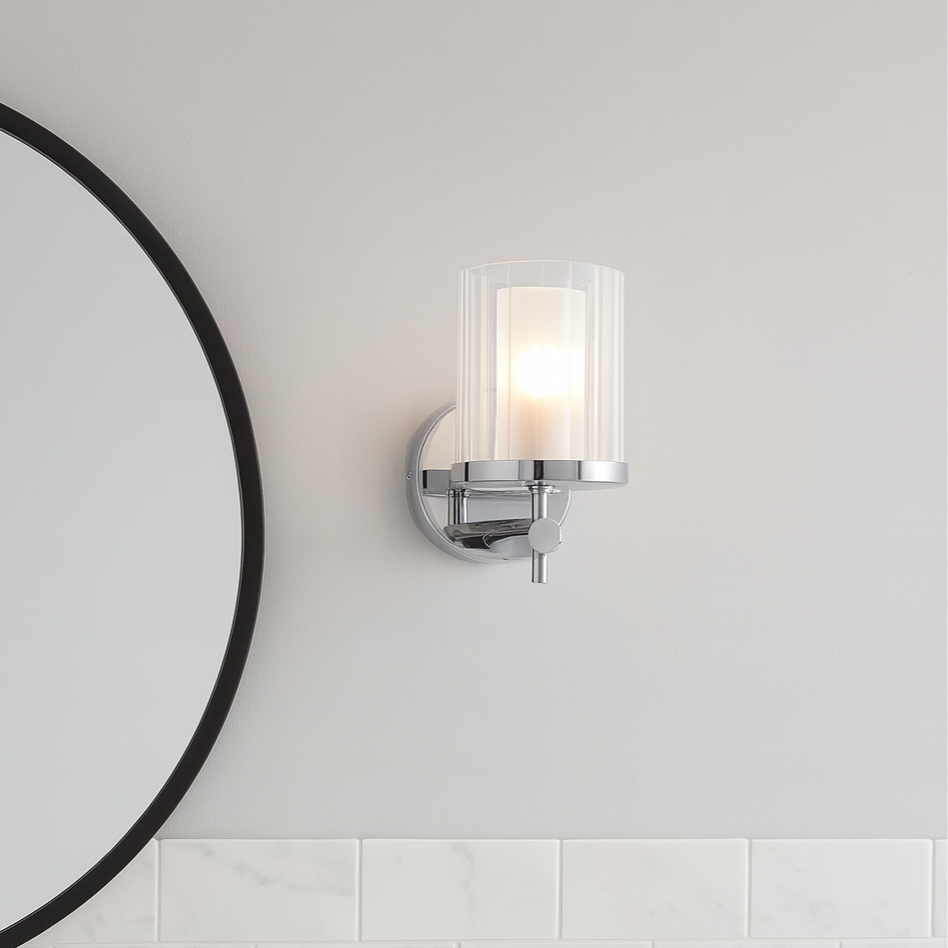 Bathroom vanity with round mirror, faucet, and light fixture.