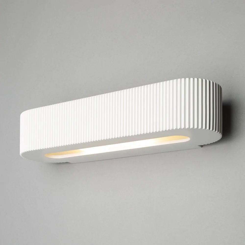 A white plaster up down plaster uplighter wall light mounted on an indoor wall, paintable in a room.