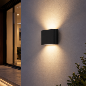 Modern outdoor wall light fixture on a house exterior at night.
