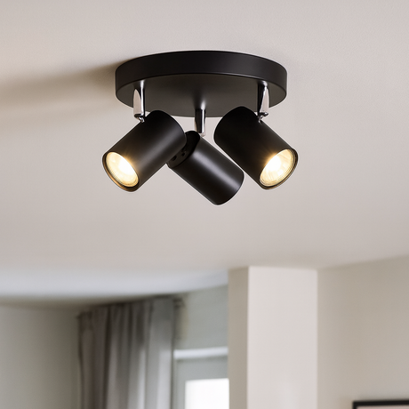 Black ceiling light fixture with three lights in a room with a window and plant.