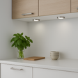 Modern kitchen with white cabinets, a plant, cutting board, and bowls on a countertop.